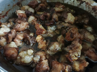 Close-up of crispy golden-brown fried fat and meat chunks simmering in oil. Perfect for culinary themes and traditional cooking visuals.