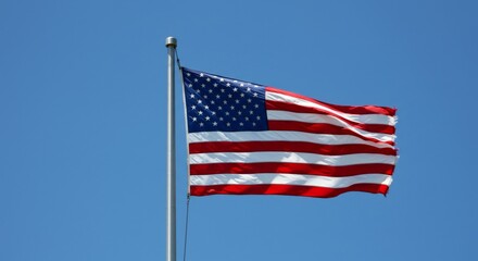 Naklejka premium American Flag Waving in a Clear Blue Sky