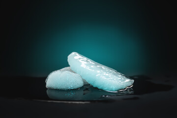 Ice melting. Melting ice chunks on dark background. Colored backlight. Selective focus