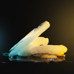 Ice melting. Melting ice chunks on dark background. Colored blue yellow backlight