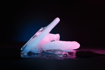Ice melting. Melting ice chunks on dark background. Colored blue-purple backlight. Selective focus