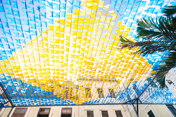 Colorful banners used to decorate the June festivities. Plastic objects are hung high up.