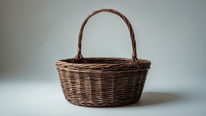 A woven wicker basket with a handle on a neutral background.
