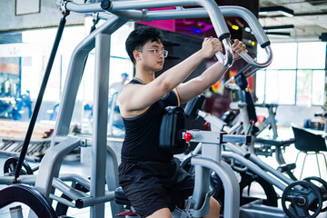 Fototapeta premium Young man performing strength training in a modern gym during daytime to improve fitness and health