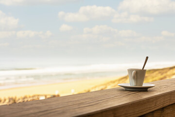 Cup of coffee or espresso placed on a wooden table facing the sea