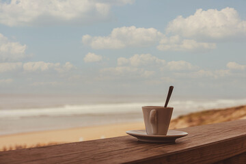 Cup of coffee or espresso placed on a wooden table facing the sea