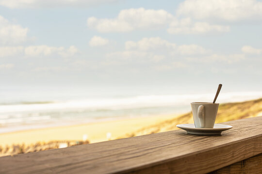 Cup of coffee or espresso placed on a wooden table facing the sea