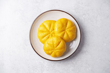 Pumpkin steamed buns with red bean paste filling in a plate