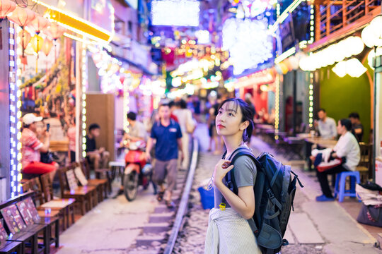 Young traveler explores vibrant street decorated with lights in an Asian city during evening hours, enjoying the lively atmosphere and local culture