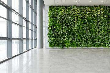A vertical indoor green wall filled with vibrant leaves enhances the clean, modern interior of a bright office hallway.
