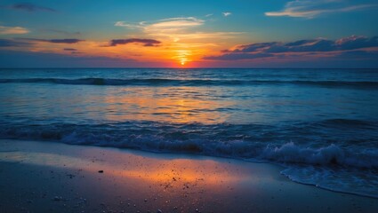 Fototapeta premium Sunset over the ocean with colorful sky, calm waves, and reflective beach surface.