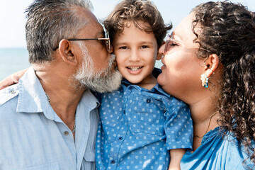 Happy family kissing smiling son outdoors, parents showing love and affection to their child