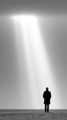 Obraz premium Dramatic monochrome sky with solitary figure under light beam