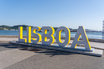 Lisbon, Portugal - May 28, 2025: Lisboa ground sign along the bank of the Tagus River and near...
