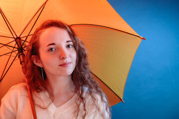 Portrait of a pretty girl smiling with eyes with a yellow umbrella on a dark blue background