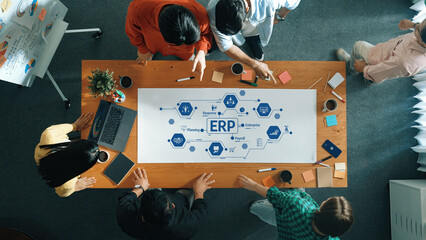 A diverse team collaborates in a modern workspace analyzing ERP concepts. The office table is filled with notes, coffee cups, and digital devices, enhancing creativity and communication. Amity