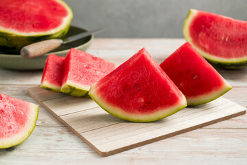 Slices of fresh watermelon on bright rustic wooden table.