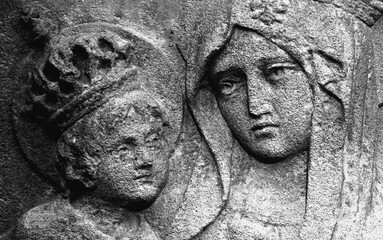 Virgin Mary with the baby Jesus Christ in her arms. Horizontal image. Stone bas-relief. Close up.