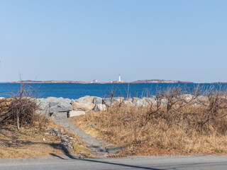 Boston light in distance with big rocks in foreground
