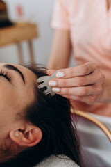 Scalp massage in spa salon using a handheld jade massager on long dark hair client