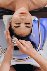 Top‑view scalp spa hair wash on long dark hair in professional salon setting