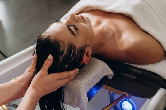 Scalp spa treatment with long dark hair on spa couch, professional hair therapy session