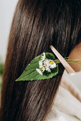 Naklejka premium Portrait of young woman with long dark hair and floral clip, showcasing natural healthy hair care