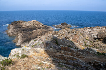 Stunning cliffs of Pacha Island, Galicia, Spain, showcasing rugged coastline and deep blue sea under a clear sky.