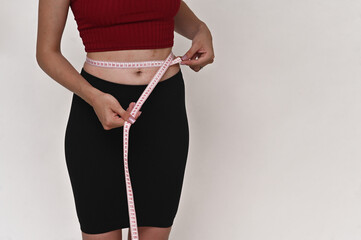 A slender young woman measures her waist. Weight loss, a concept