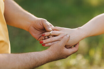 Adults, elderly people put gold rings on their fingers outdoors in the forest at the ceremony....
