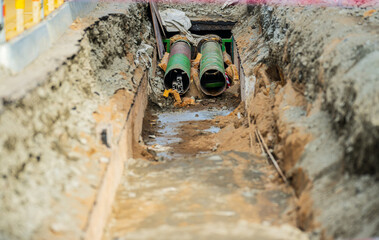 Underground construction trench with exposed pipes.