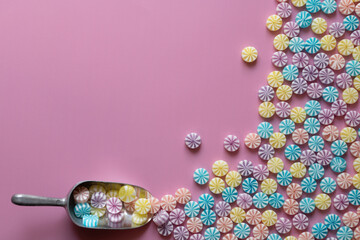 A view from above on a pink background. A small metal scoop appears to be scattering lots of...