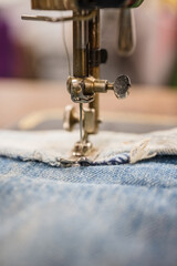 Antique sewing machine stitching denim.