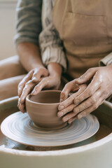 Adult and child hands shaping clay on pottery wheel
