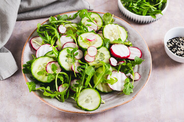 Cucumber, radish and greens salad mix on a plate on the table