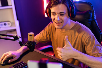 Host channel of gaming smart streamer playing online game to be winner, wearing headphone with viewers live steaming on media social online for selected team competition at neon light room. Pecuniary.