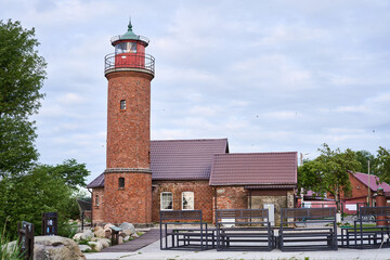 A charming brick lighthouse surrounded by lush nature on the stunning coast, perfect for maritime adventure themes