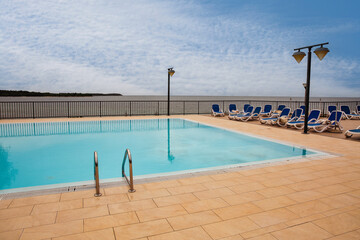 Plakat Empty swimming pool with sea view and sun loungers