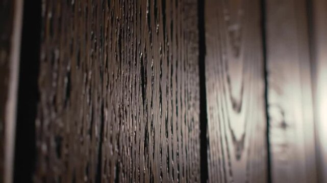 Close up shot of a dark brown wooden surface with vertical planks and visible wood grain texture detail