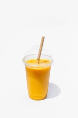 Plastic glass of passion fruit or maracuya or granadilla juice  with a paper straw on white background. Healthy drink. Take away food.