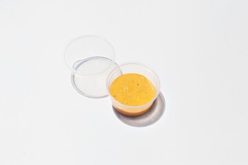 creamy orange Peruvian sauce in plastic little jar - crema de rocoto - on white background. Take away fast food condiment. 