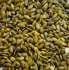 Healthy green pumpkin seeds arranged on a clean white surface ready for snacking