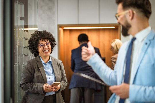 mature african american woman talk with male colleague in hallway