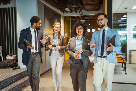 Multicultural colleagues talk and smile while walk through the company