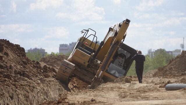 An accident involving an excavator. The excavator fell under the ground. The excavator fell on its side.