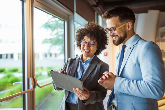 male and female colleagues use tablet together and discuss work