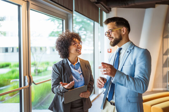male and female colleagues use tablet together and discuss work