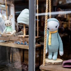 Handmade crochet dolls in a shop window.