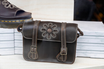 Brown leather satchel bag with flower detail.