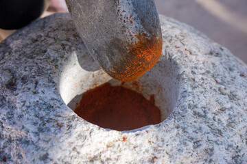 Ancient Stone mortar grinding red peppers en Cachi, Salta, Argentina